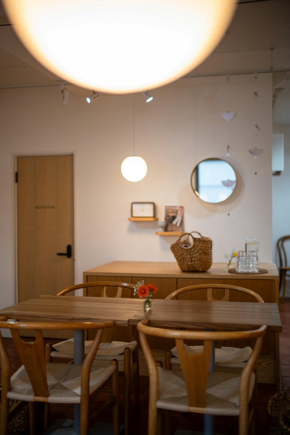 Warmly lit café dining area with wooden tables, chairs, and fresh flowers